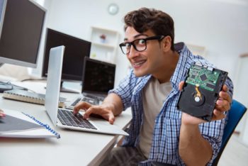 Technician working on a computer holding a broken hard drive