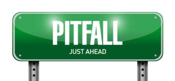Green road sign that reads " Pitfall: Just Ahead"